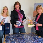 Das Foto zeigt von links: Paula Dangberg (Mitarbeiterin im Stadtmarketing, Bürgermeistern Anne Rodenbrock-Wesselmann und Anne Prell (städtisches Tourismusbüro), mit den drei Hauptpreisen und den Gewinnen für die Plätze vier bis zehn, ein Haller Wohlfühlhandtuch.
