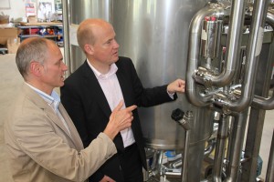 Gerhard Wellmann (links) entwickelt und produziert mit 80 Mitarbeitern Anlagentechnik für keimfreie Produktionsprozesse. MdB Ralph Brinkhaus (rechts) zeigte er jetzt eine innovative Biosprit-Anlage für den Einsatz in Entwicklungsländern.